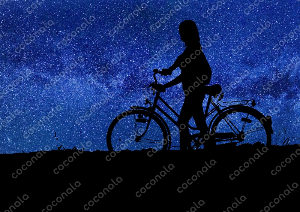 満天の星空と自転車を押して歩く女性のシルエット