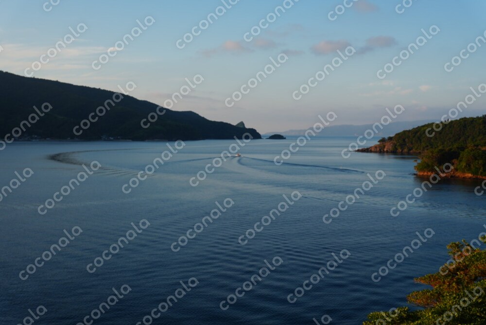 離島の穏やかな海に浮かぶ船の写真